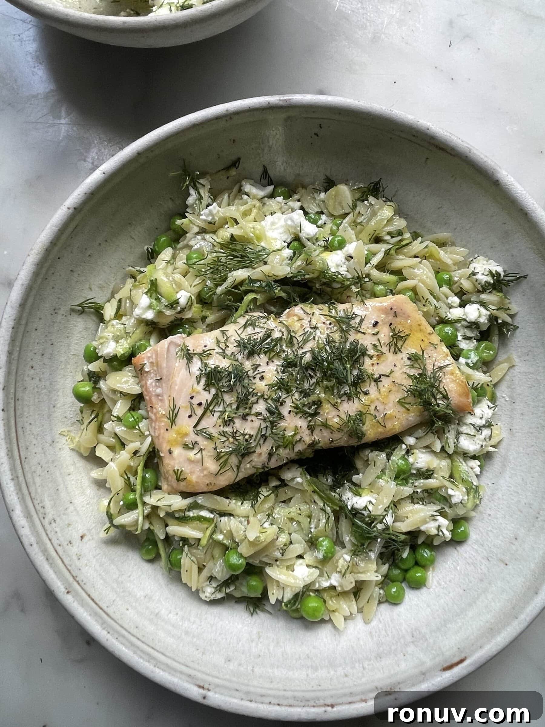 Creamy Lemon Orzo with Feta and Fresh Herbs 4 lemon orzo with feta topped with salmon in a grey bowl.