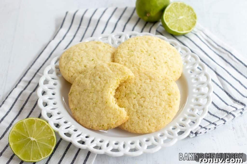 Zesty Lime Sugar Cookies with Citrus Glaze 11 lime sugar cookies on a plate on a striped napkin with one missing a bite
