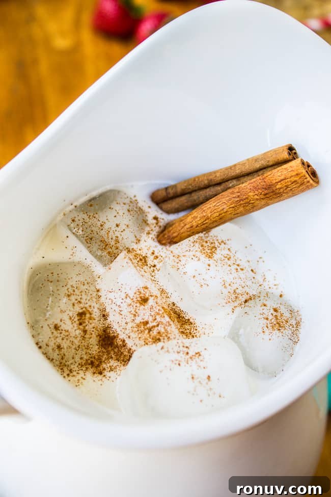How to Make Authentic Mexican Horchata 3 a white pitcher of horchata with cinnamon sticks and ice cubes.