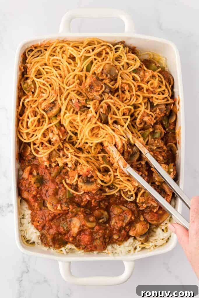 mixing the spaghetti into the sauce