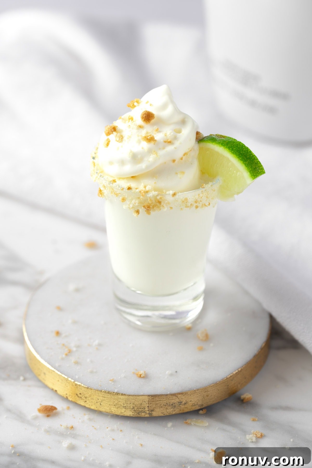 Key Lime Pie Shot Recipe: Creamy Citrus Shooter 2 A Key Lime Pie Shot topped with whipped cream, graham cracker sprinkles and a mini slice of lime.