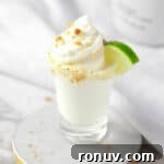 A Key Lime Pie Shot topped with whipped cream, graham cracker sprinkles and a mini slice of lime.