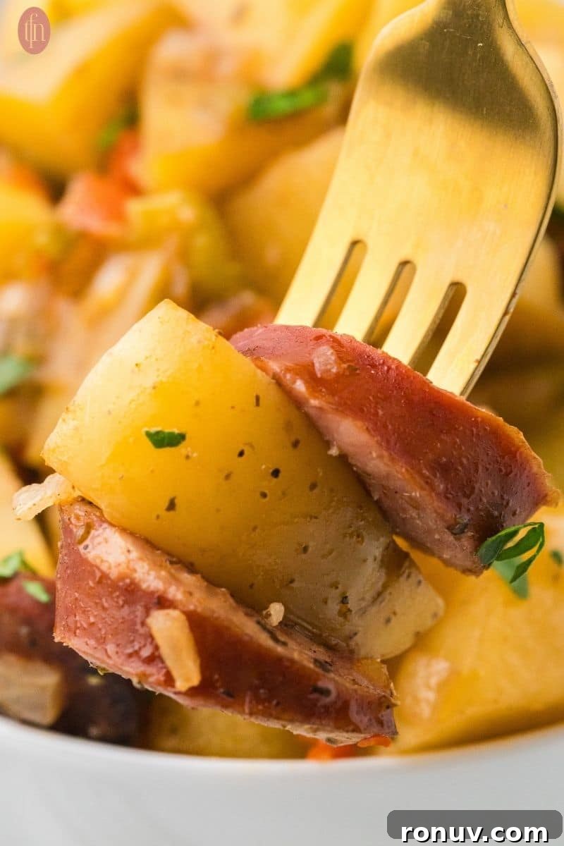 Slow Cooker Sausage and Potatoes 5 a fork stacked with crockpot sausage & potatoes sprinkled with parsley.