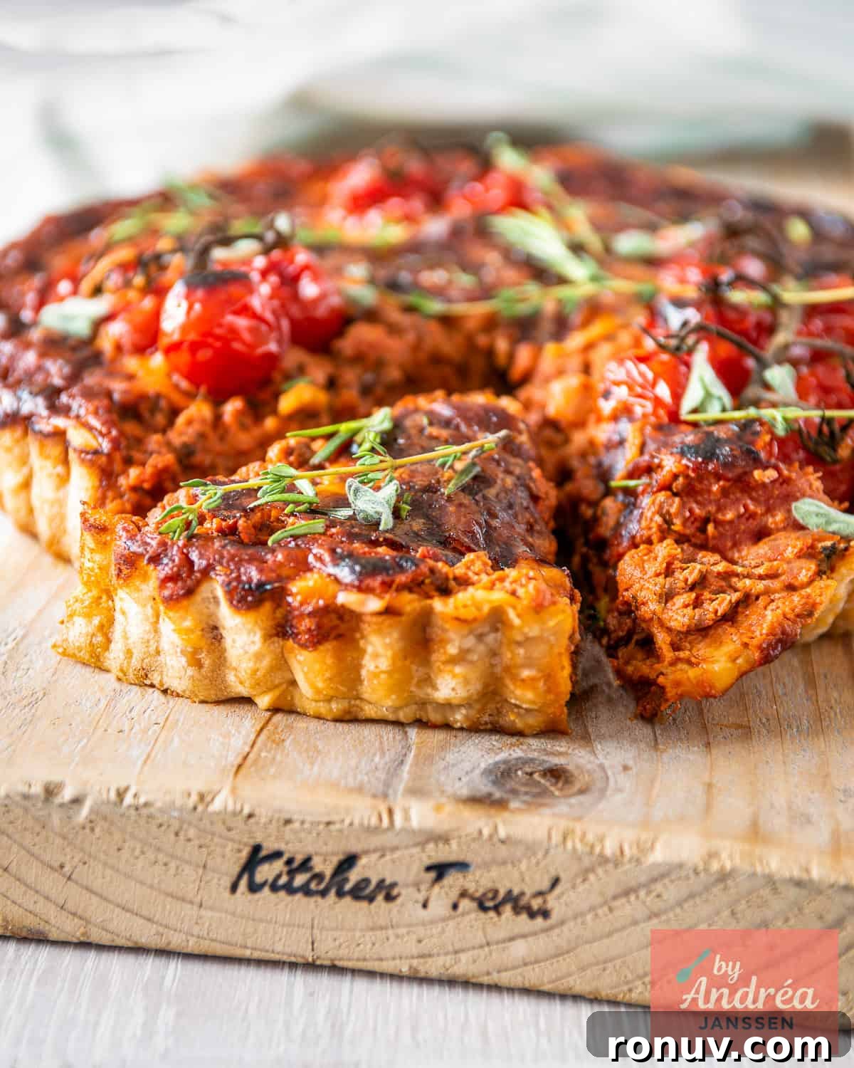 Bolognese Quiche Recipe with Ground Beef and Parmesan 2 A bolognese quiche on a wooden board with a wedge cut out.