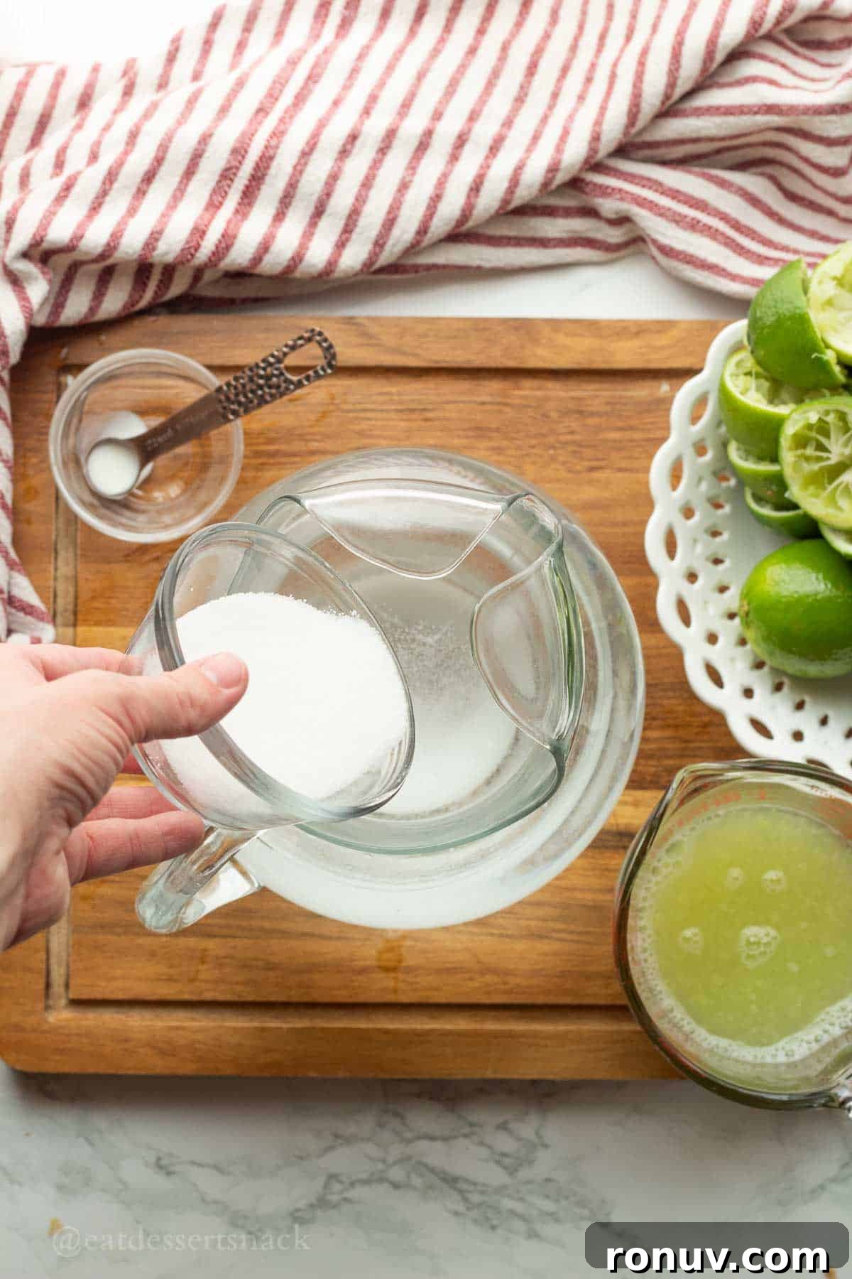 Coconut Lime Cooler: Tropical Drink Recipe 5 Pouring sugar into pitcher of water.
