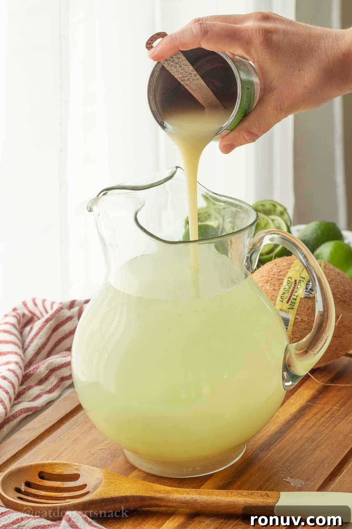 Coconut Lime Cooler: Tropical Drink Recipe 6 Pouring coconut condensed milk into pitcher.