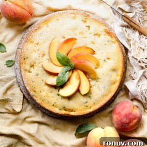 Peach Ricotta Cake with Fresh Basil 5 Single layer cake topped with yellow peaches and basil on a wood board.