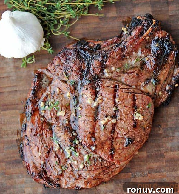 grilled ribeye on a wooden board with garlic nearby