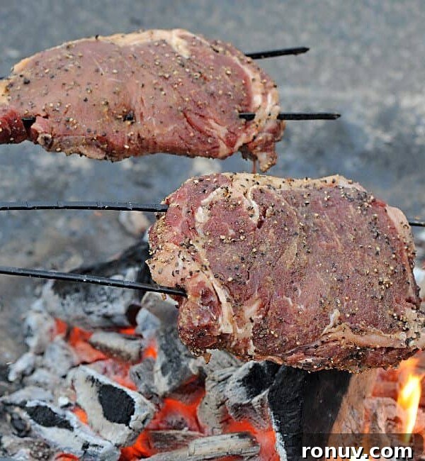 2 ribeyes on skewers over a campfire