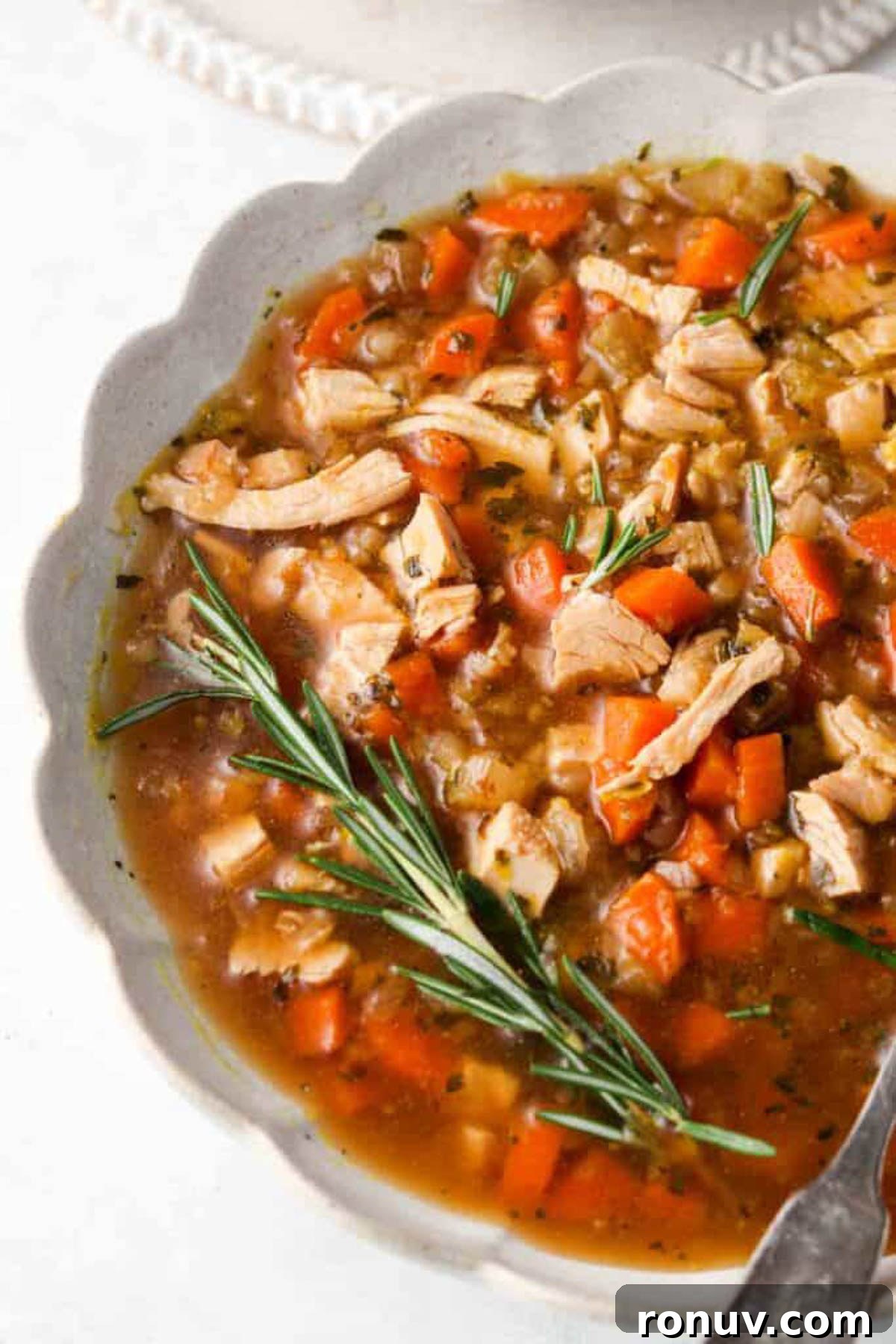 Instant Pot Leftover Turkey Soup Recipe with Vegetables 4 Bowl of instant pot turkey soup in a white bowl with a fresh spring of rosemary.