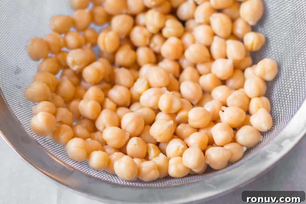 Creamy Homemade Hummus Recipe with Garlic and Lemon 2 chickpeas in a metal mesh strainer