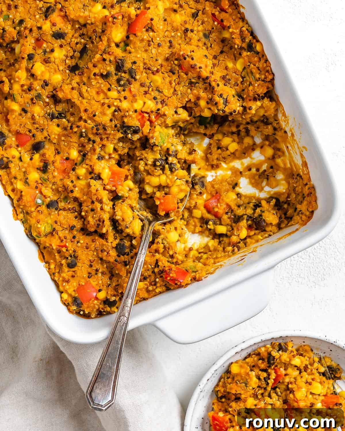 Baked Black Bean and Quinoa Casserole 2 completed Easy Black Bean Quinoa Casserole in a baking dish against a white surface with a serving on a plate