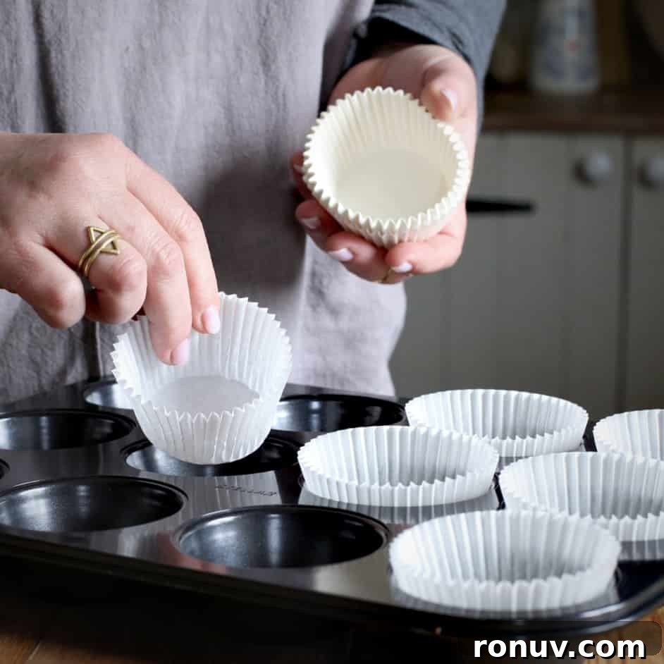 Savory Cheese and Red Onion Muffins: Budget-Friendly Snack 4 Woman hands placing white paper muffin cases into a black muffin tray