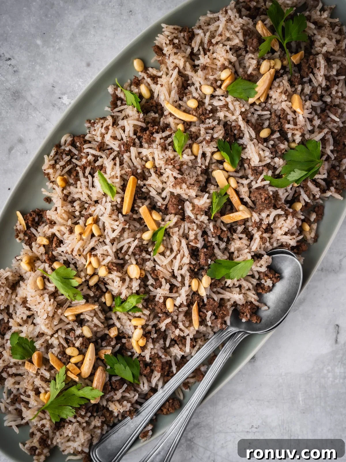 Lebanese Hashweh: Spiced Rice with Ground Beef 11 Platter with spiced rice and ground beef garnished with parsley and toasted nuts with a side of plain yogurt.