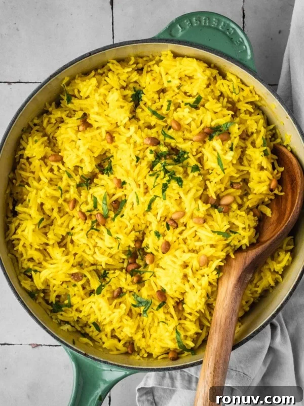 Mediterranean yellow rice in a pot garnished with pine nuts and fresh parsley.
