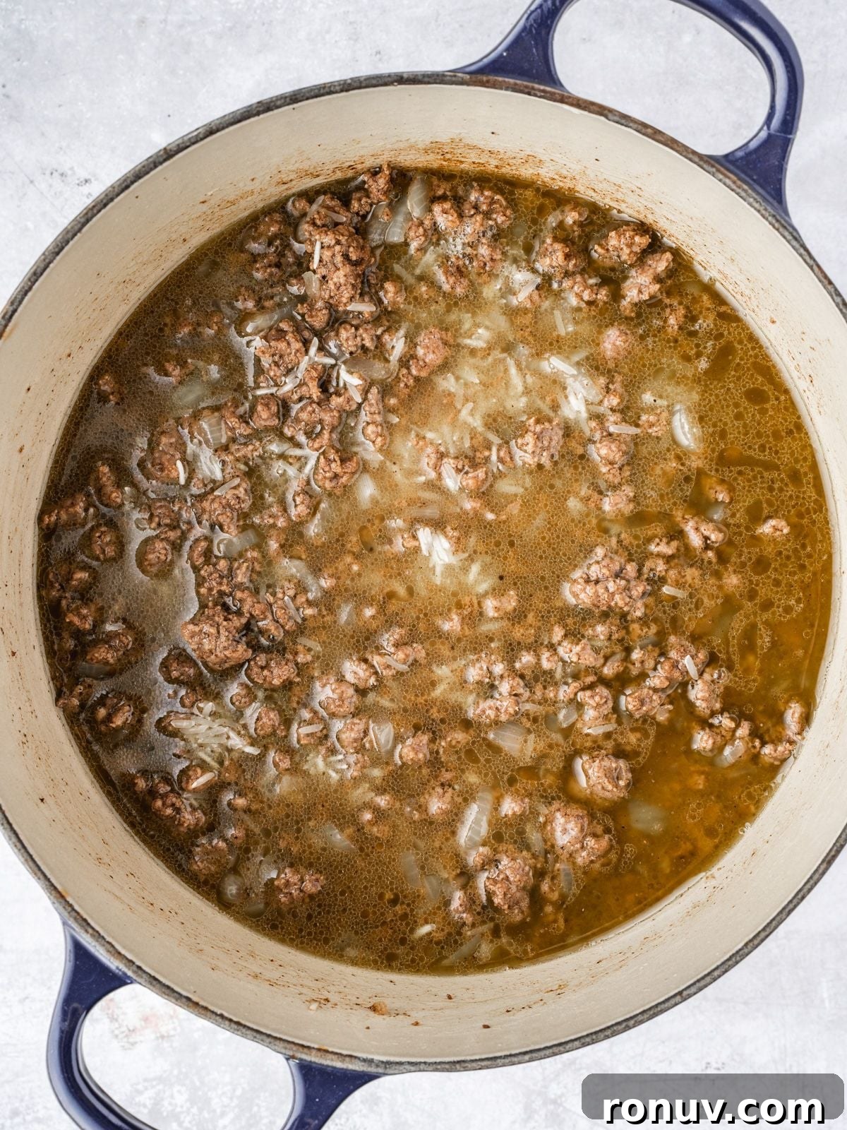 Lebanese Hashweh: Spiced Rice with Ground Beef 8 Adding the chicken broth to the pot with the cooked beef and uncooked rice.