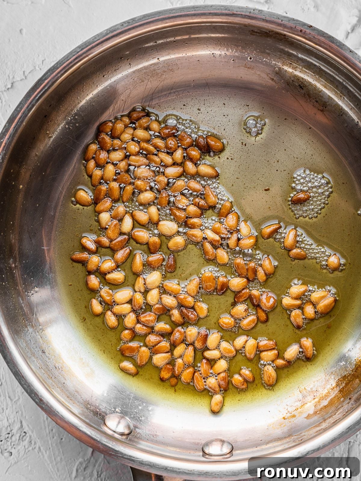 Lebanese Hashweh: Spiced Rice with Ground Beef 10 Pine nuts frying in a pan with butter.