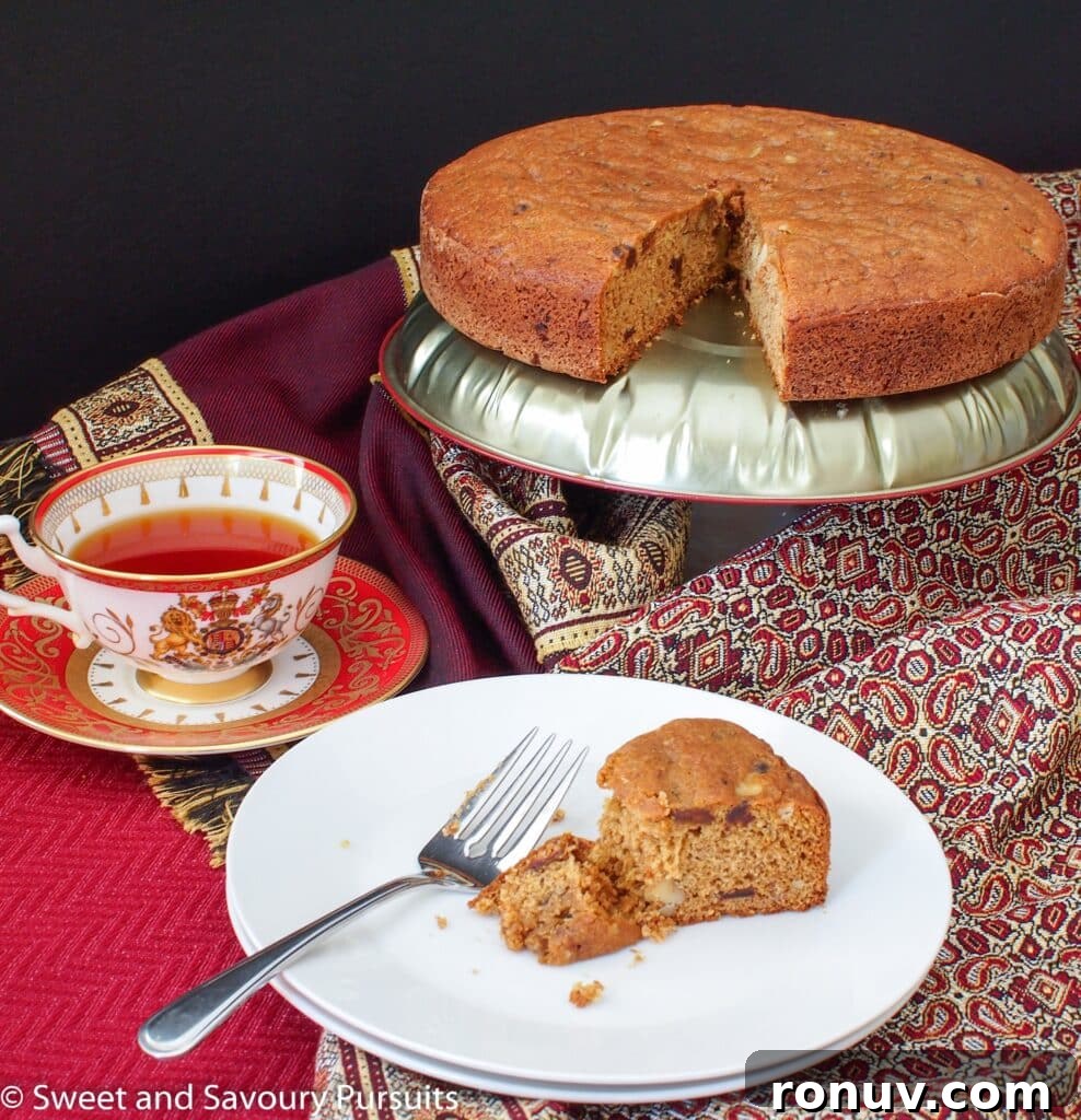 Partially eaten slice of date cake served with a cup of tea.