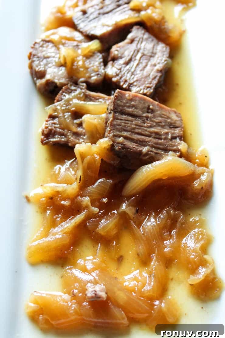 Beer-Braised Beef with Caramelized Onions Recipe 5 Close up of beef with onions on white platter.