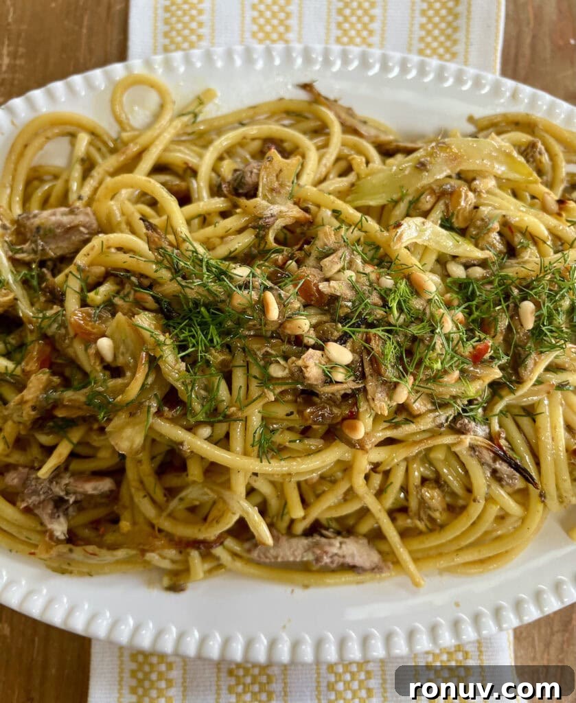 Authentic Sicilian Pasta con Sarde Recipe 2 Finished Sicilian pasta con sarde recipe with fennel fronds garnish on white platter over decorative towel.