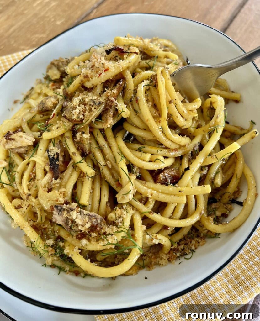 Authentic Sicilian Pasta con Sarde Recipe 7 Fork with twirled Sicilian sardine pasta in white pasta bowl.