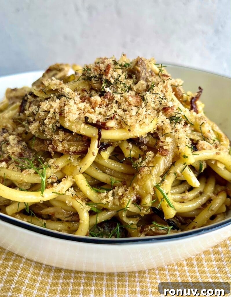 Authentic Sicilian Pasta con Sarde Recipe 3 Close up of Sicilian sardine pasta with toasted breadcrumb topping in white bowl over yellow towel.