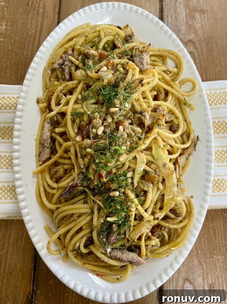 Authentic Sicilian Pasta con Sarde Recipe 10 Finished Sicilian pasta con sarde recipe with fennel fronds garnish on white platter over decorative towel.