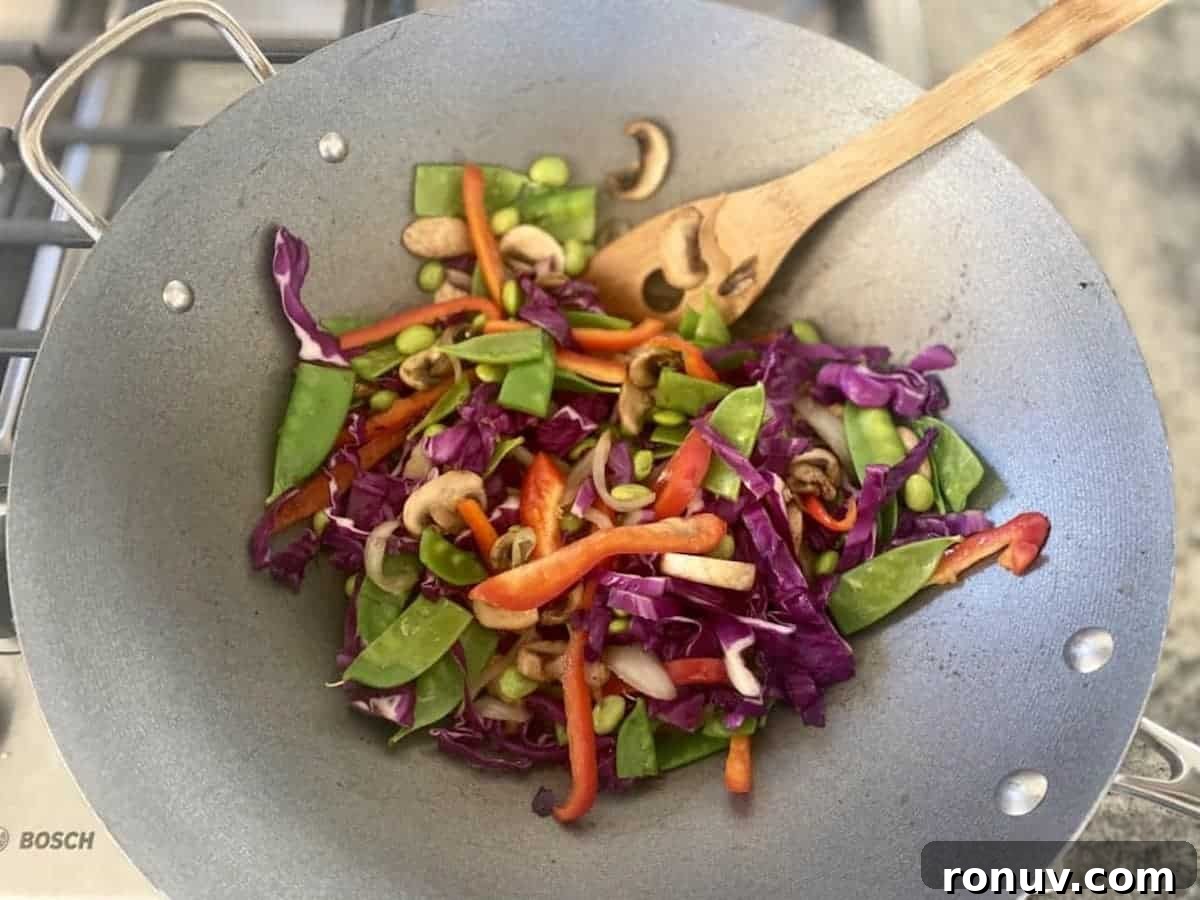 15-Minute Garlic Butter Noodles Recipe 5 Seared vegetables are cooking in a wok on the stove.