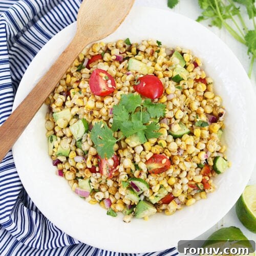 roasted corn salad in a white serving bowl garnished with a sprig of cilantro