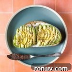 An avocado tartine on a blue plate with a vintage knife.