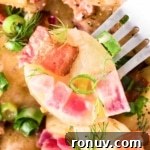 Bavarian potato salad with bacon, red onions, and dill on a fork.