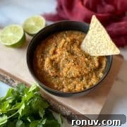 A bowl of pineapple habanero salsa on a wooden cutting board with limes and cilantro.