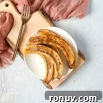 Air fryer bananas on a white plate with a pink linen and a copper fork.