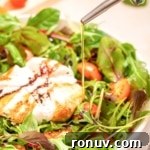 A bowl of burrata caprese salad with olive oil being poured over it.
