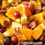 A closeup of Thanksgiving Fruit Salad with grapes, pears, apples, oranges, and pecans.