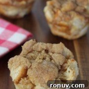 Four cinnamon crumb muffins on a wooden surface.