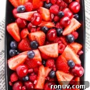 A rectangular dish filled with a variety of fresh red and purple berries.