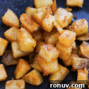 A plate of diced, crispy golden-brown roasted potatoes.