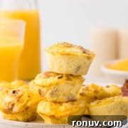 A plate with a stack of four mini quiches and a glass of orange juice.