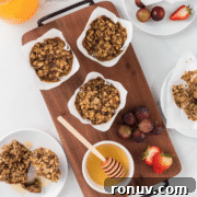 A wooden tray with four oatmeal muffins and a honey dipper.