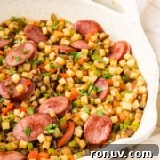 A pan with a vegetable medley mixed with slices of sausage.