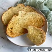 Three slices of toasted bread on a white plate on a white marble counter.