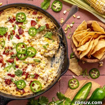 Jalapeno corn dip in a skillet with a spoon and chips on the side.