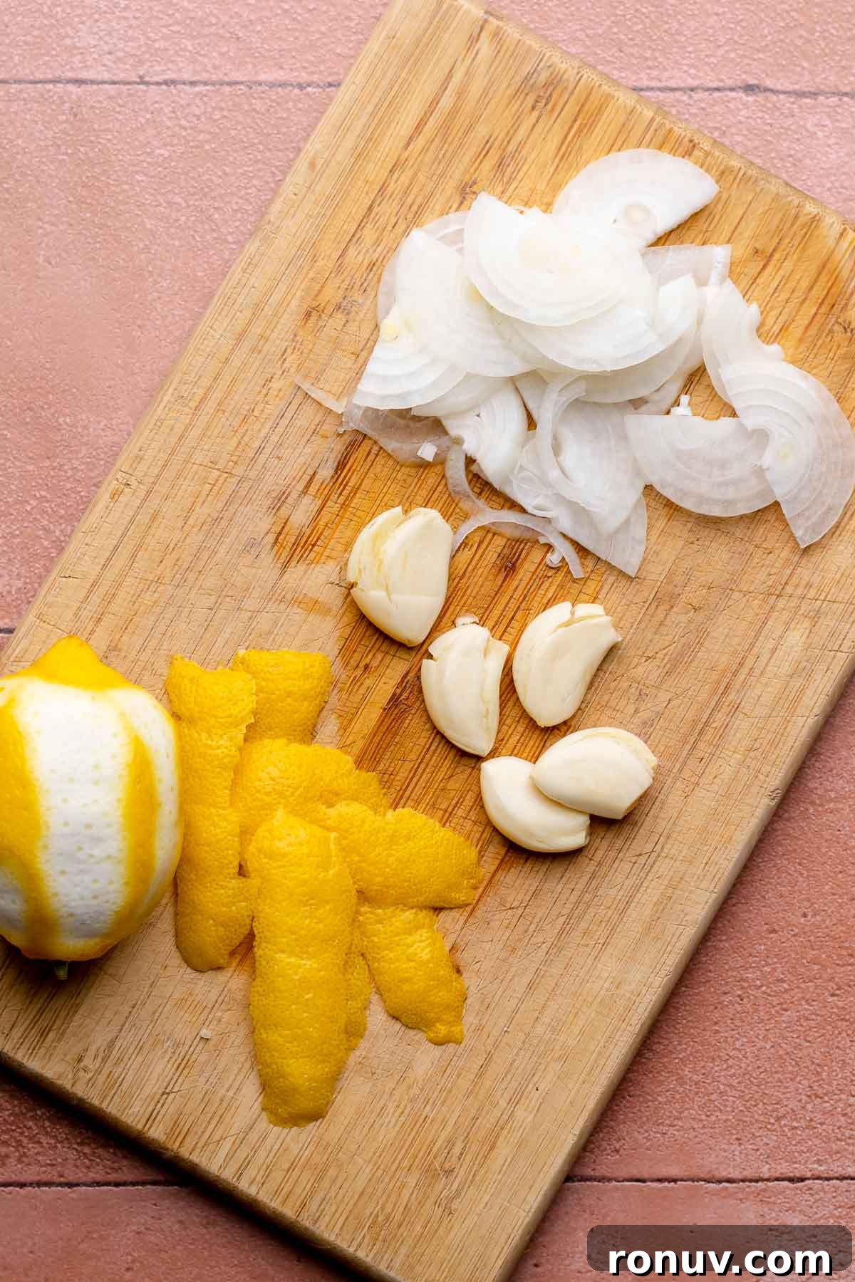 Herb Roasted Olives with Burrata Recipe 4 Lemon, garlic, and sliced onions on a cutting board.