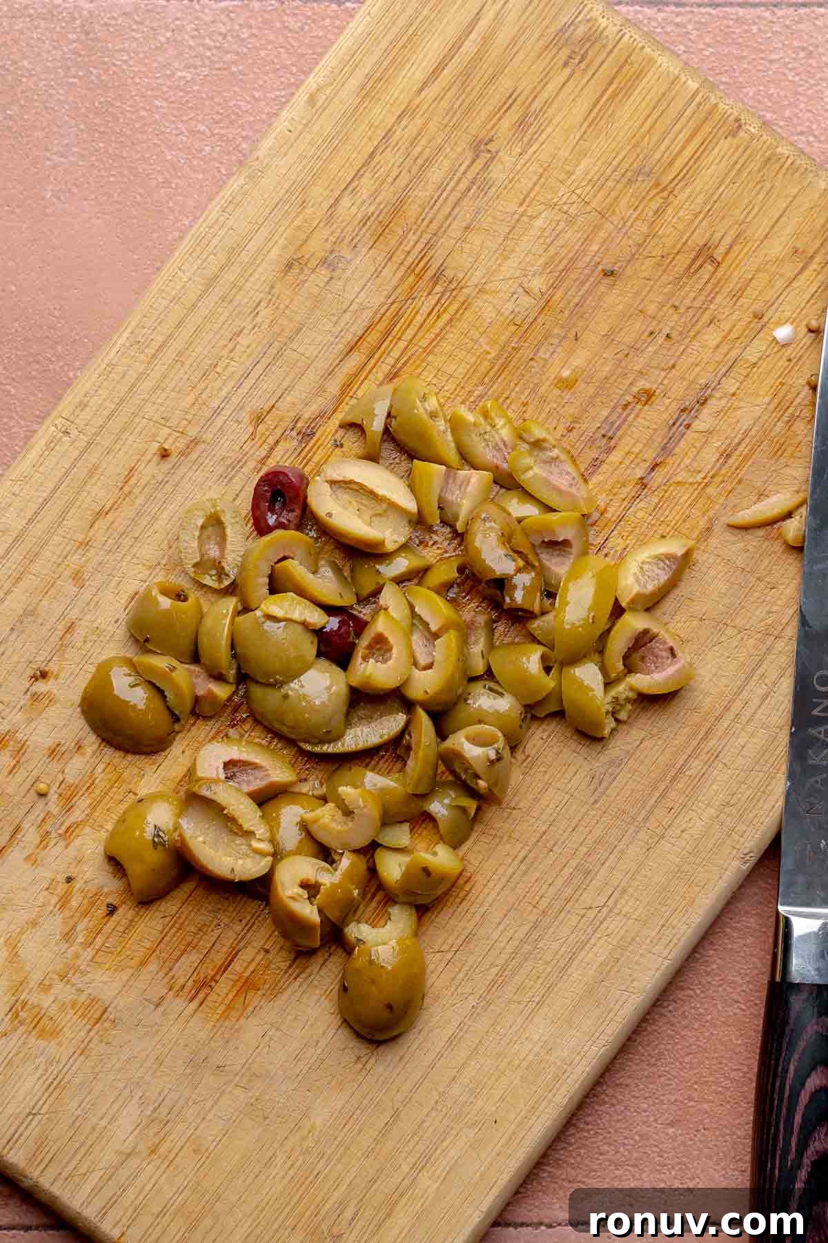 Herb Roasted Olives with Burrata Recipe 5 Sliced olives on a cutting board.
