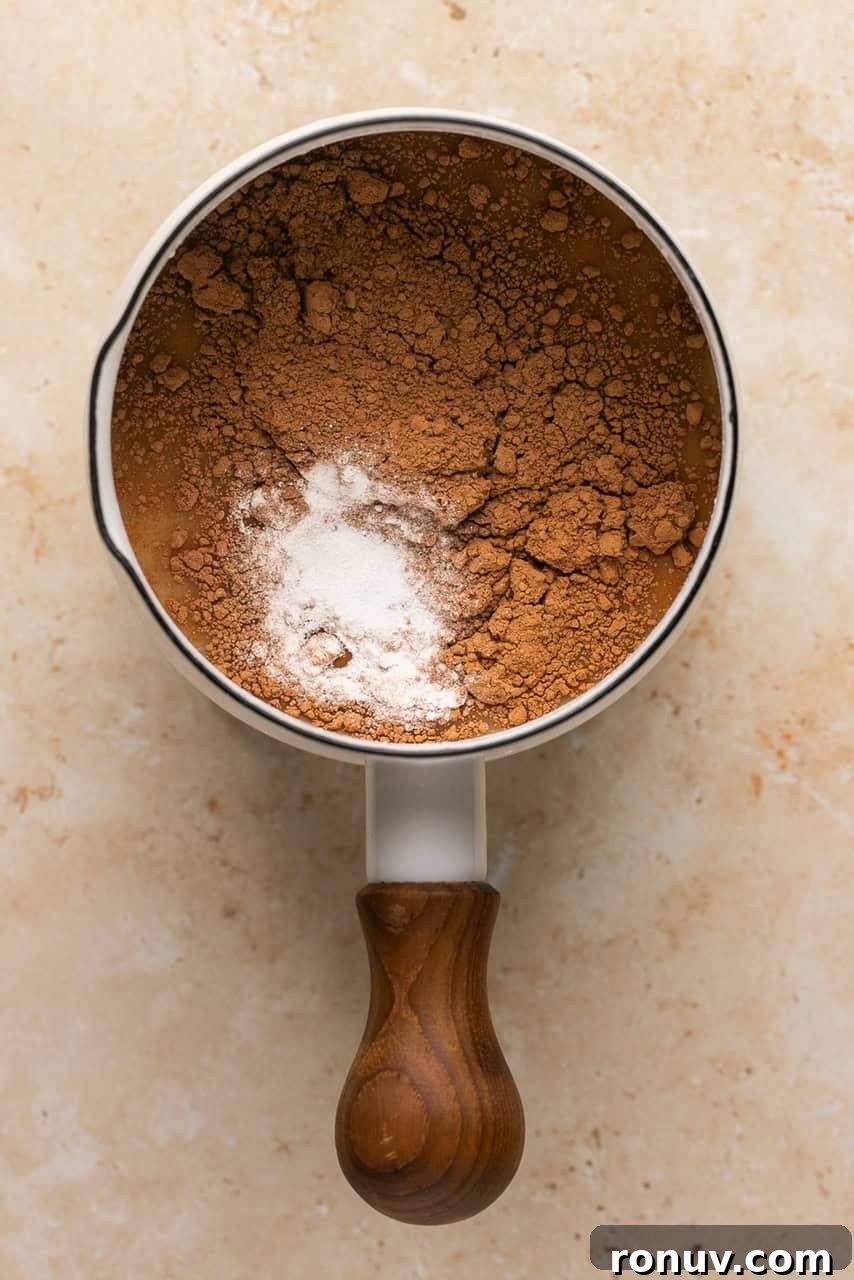 a small sauce pan with collagen, broth, cocoa powder, and maple syrup in it