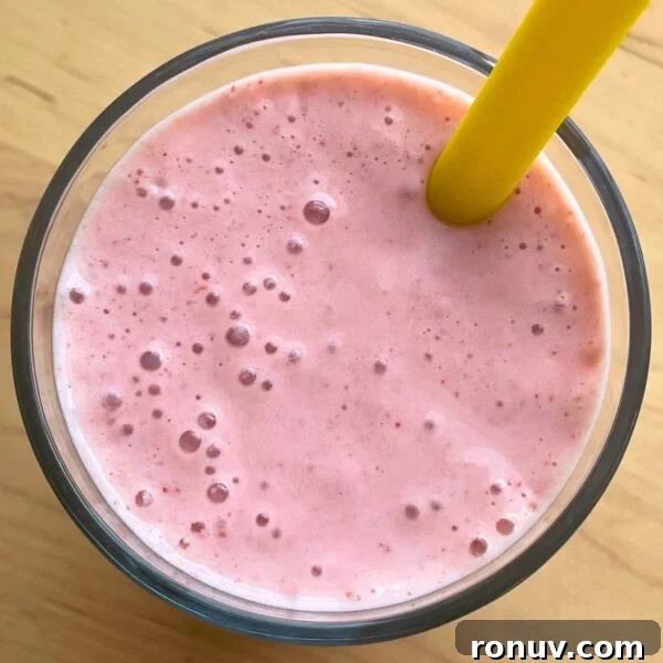 A close-up of a strawberry banana smoothie with Greek yogurt with a yellow straw.