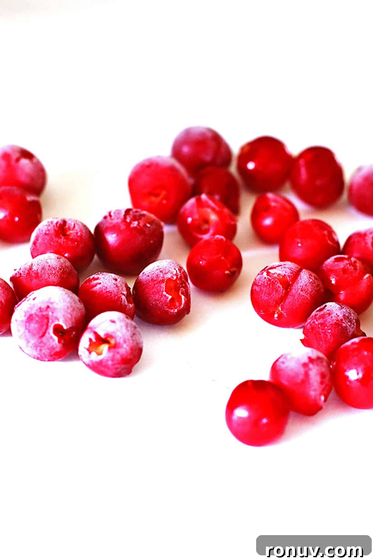 Frozen tart cherries on baking sheet covered with white parchment paper