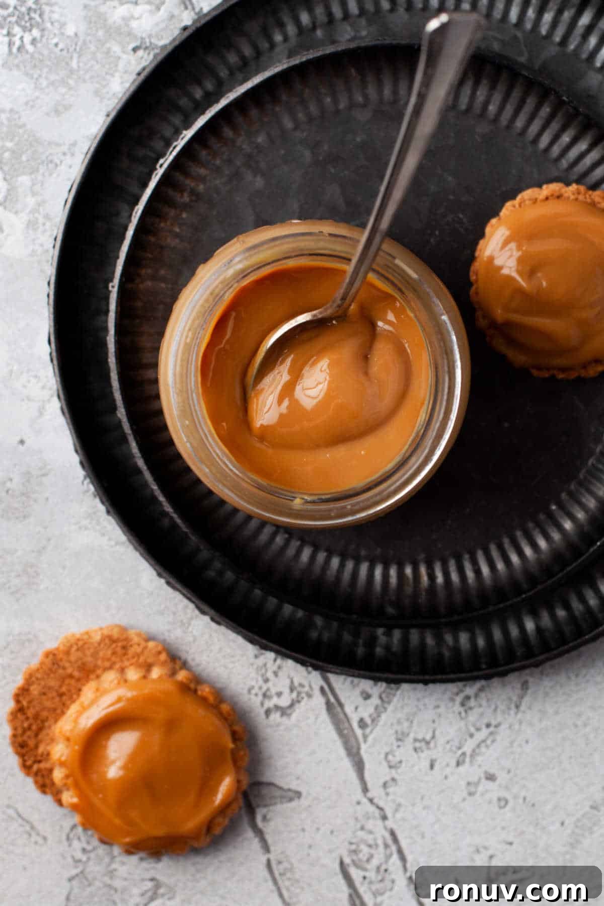 Instant Pot Dulce de Leche Recipe: Creamy Caramel 5 A jar of dulce de leche with a spoon on a platter with some cookies.