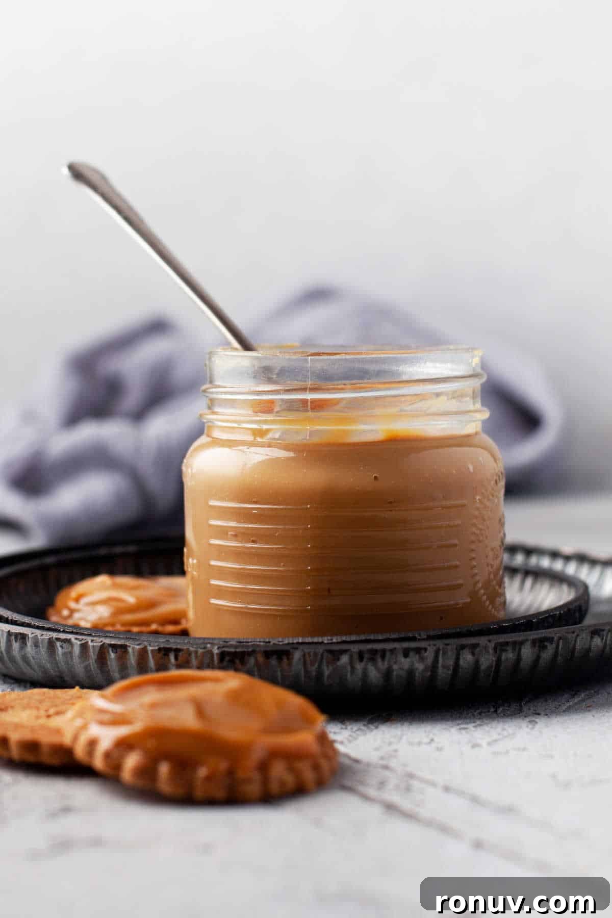 Instant Pot Dulce de Leche Recipe: Creamy Caramel 6 A glass jar of dulce de leche with a spoon in it.